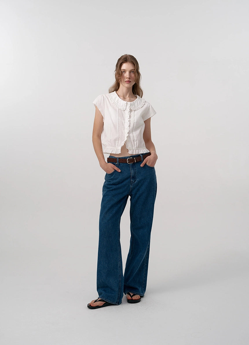 The Daina Ruffle Collar Blouse features a delicate lace trim along the hem, adding a refined and expert touch to its design. Crafted from a soft, ivory cotton fabric, this blouse combines sophisticated details such as a ruffled collar and precise stitching to ensure both elegance and durability. Ideal for those who appreciate meticulous craftsmanship and understated femininity.