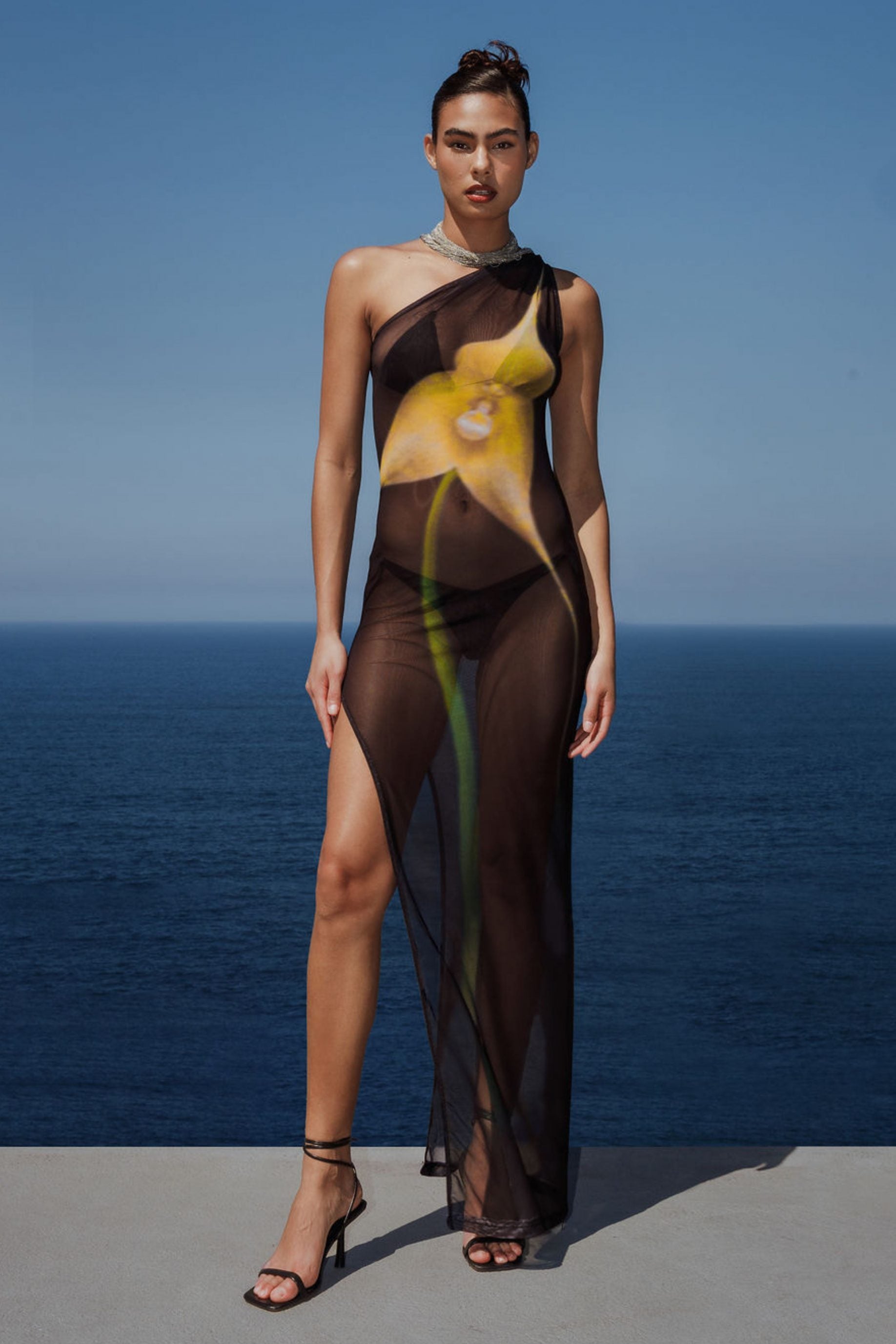 Step up your fashion game with the Orquidea Maxi Dress. The deep leg slit and exclusive digital print elevate your look, while the transparent material exudes elegance. Perfect for adding a touch of sophistication to any occasion.