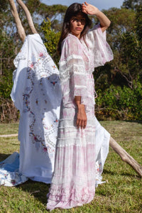 Indulge in elevated elegance with the Angel Maxi Dress. This duster boasts intricate layers of tulle and macrame` panels, made from delicate chiffon. The elastic and drawstring waist create a flattering silhouette while the button-through bodice and skirt add a unique touch. A must-have for layering and elevating any outfit.