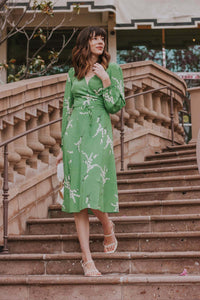 Show off your playful side in the Violette Midi Dress! This stunning lightweight silk dress features a white floral print on a vibrant green background. With 3/4 length sleeves and a comfortable wrap style, you can adjust the waist with the string tie closure. Embrace your love for summer in this unique and stylish dress!