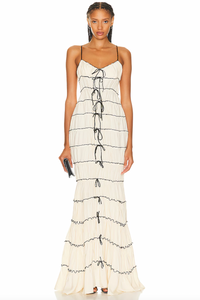 The Ruffle Tunnel Gown features a discreet side zipper closure for a seamless look and tie embellishments that enhance the front and back seams with delicate detail. Crafted from tiered ruched fabric with a luxurious satin finish, this gown offers both texture and a subtle sheen, combining elegant structure with fluid movement for a sophisticated silhouette.