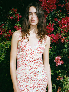 The Zoë in Jazz Devoré by Realisation Par embodies effortless summer elegance with its soft blush pink fabric and delicate red velvet polka dot pattern. This lightweight, sheer dress includes a removable underslip for customizable coverage. Expertly crafted with a plunging V-neckline, a sculpting panelled waist, and a fluted skirt, it flatters the figure while allowing graceful movement. 