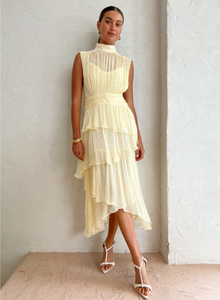 Introducing the Gina Sleeveless Ruched Midi Dress in Limoncello - a must-have for any special occasion. Crafted from semi-sheer chiffon, this dress boasts a high neck and adjustable rouleau straps for a perfect fit. With its fitted waist and asymmetrical tiered skirt, this dress exudes elegance and style. Perfect for formal events and celebrations.