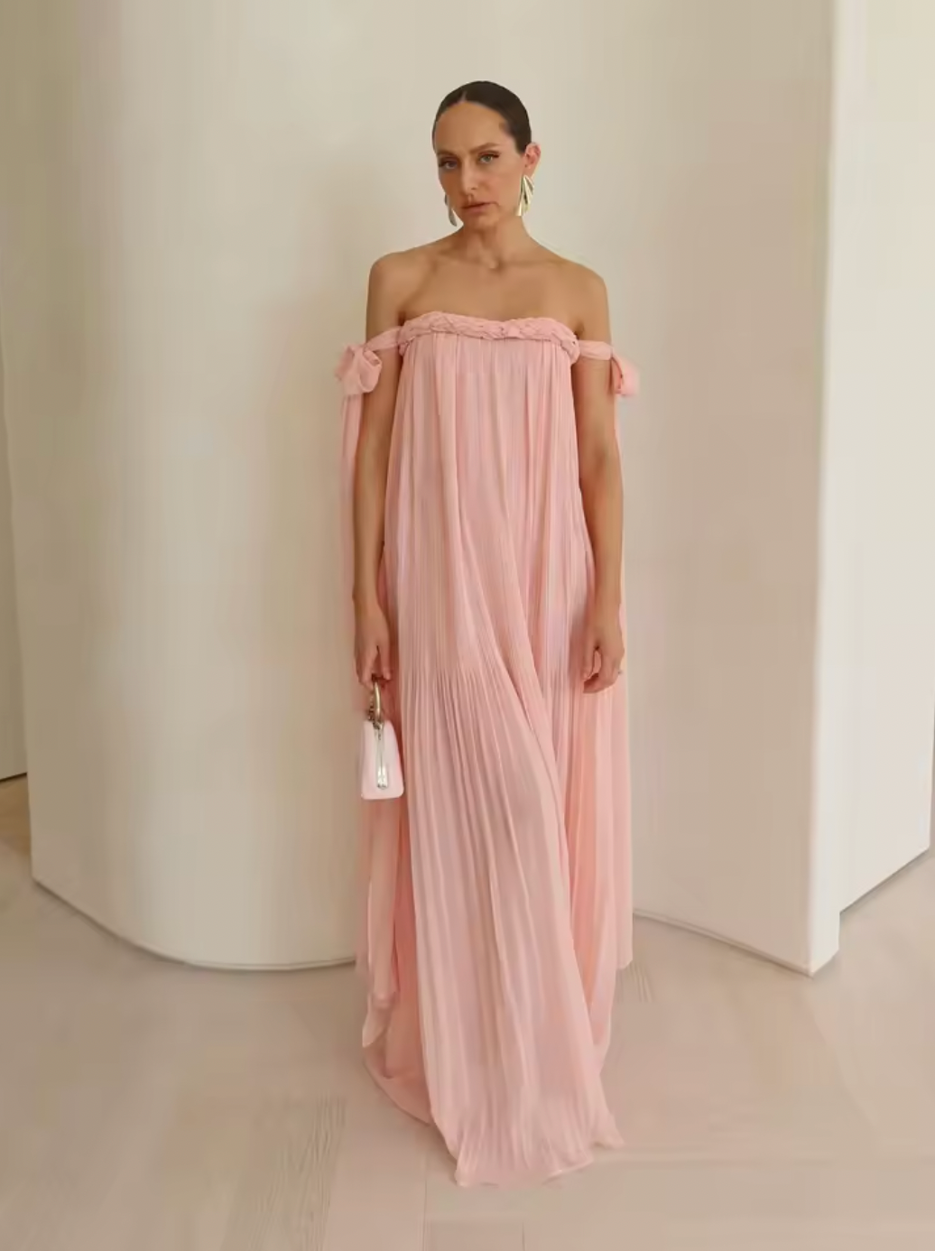 Elevate your elegance with this draped floor-length dress featuring an intricate braided neckline and a corset bodice lining for subtle structure. The tie arm straps flow gracefully into a train, complementing the relaxed silhouette. An invisible back zip closure ensures a seamless finish, while the sheer tulle lining adds delicate dimension to this sophisticated design.