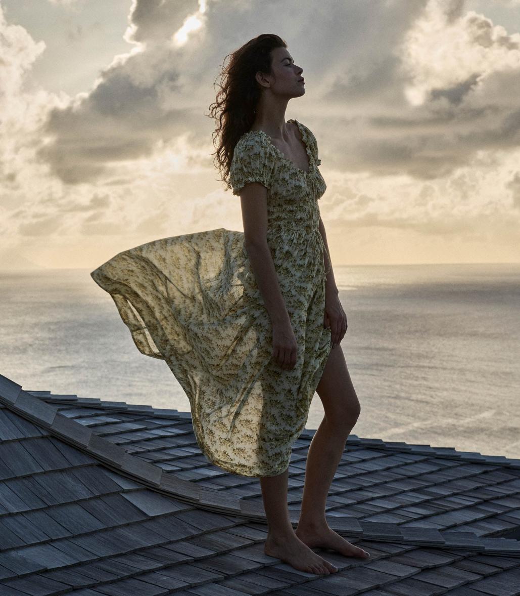 Crafted from soft, lightweight organic cotton voile, the Ashlynn Dress in Citron Rosier Floral by Doen blends Victorian elegance with modern comfort. Featuring short puffed sleeves, a scoop neckline with a functional center tie, and delicate ruffled cuffs, this dress exudes vintage charm. The smocked bodice ensures a flattering fit, complemented by an adjustable waist tie, while the full, ankle-grazing skirt offers graceful movement. Ideal for those seeking refined style with breathable, sustainable fabric.