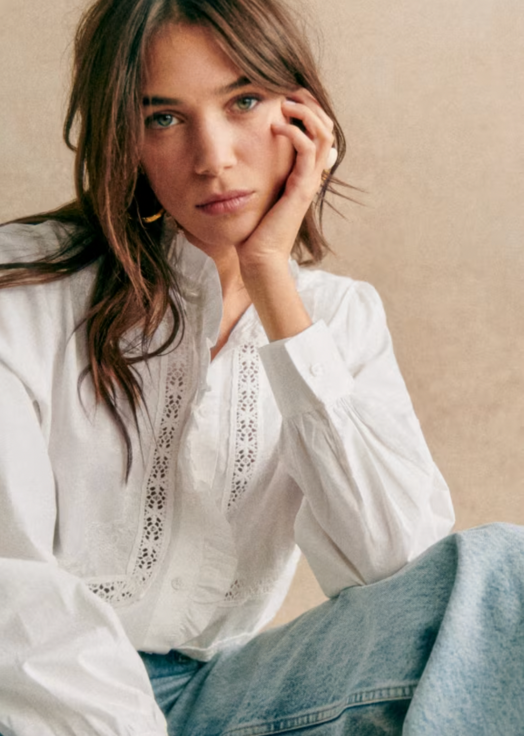 The Ulysse Shirt by Sezane features a sophisticated high collar accentuated by a delicate gathered ruffle surrounding both the collar and placket. Crafted with an embroidered openwork lace band on the body, it combines intricate detailing with refined texture. Finished with elegant mother-of-pearl buttons, this long-sleeved shirt embodies timeless craftsmanship suitable for a polished, expert wardrobe.