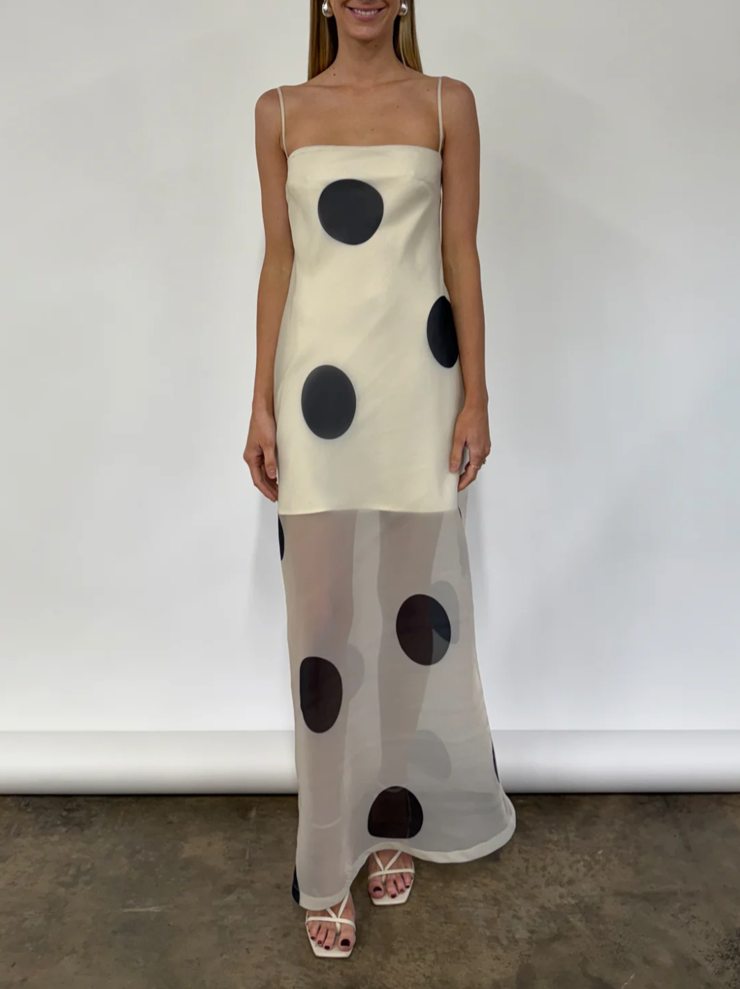 The Mila Maxi Dress in Ivory Polka by Nicole features sheer organza adorned with striking polka dots, shaping a sleek column silhouette. Its half-lined design and elasticated back ensure comfort and adaptability, while the option to wear it with or without straps provides versatile styling choices perfect for refined occasions.