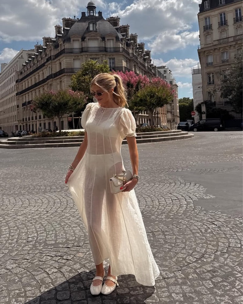 The Emory Dress features delicate chiffon fabric with elegant puff sleeves and elastic cuffs, creating a romantic silhouette. Its unlined, sheer design reveals undergarments, enhancing its ethereal appeal—please note undergarments are not included. A discreet back zip closure ensures a smooth fit, while hand wash care maintains the dress's lightweight texture and shape. Ideal for those seeking a sophisticated statement piece with a modern, airy feel.
