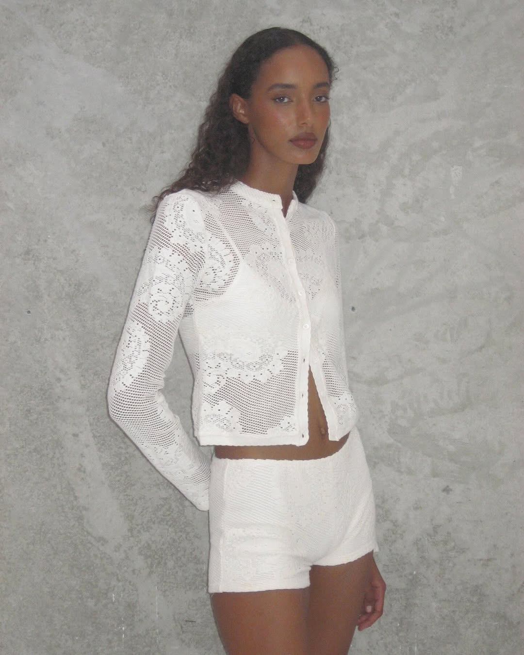 Elevate your wardrobe with the Dom Set by With Jean, expertly combining refined craftsmanship and elegant design. The Dom Top is a long-sleeve cardigan featuring a button-up front, a polished neckline collar, and delicate scalloped trim, enhanced by custom hand-drawn crochet lace for a sophisticated finish. Complementing the top, the Dom Shorts offer comfort with a fully lined interior and an elasticated waistband, adorned entirely with the same intricate crochet lace. 