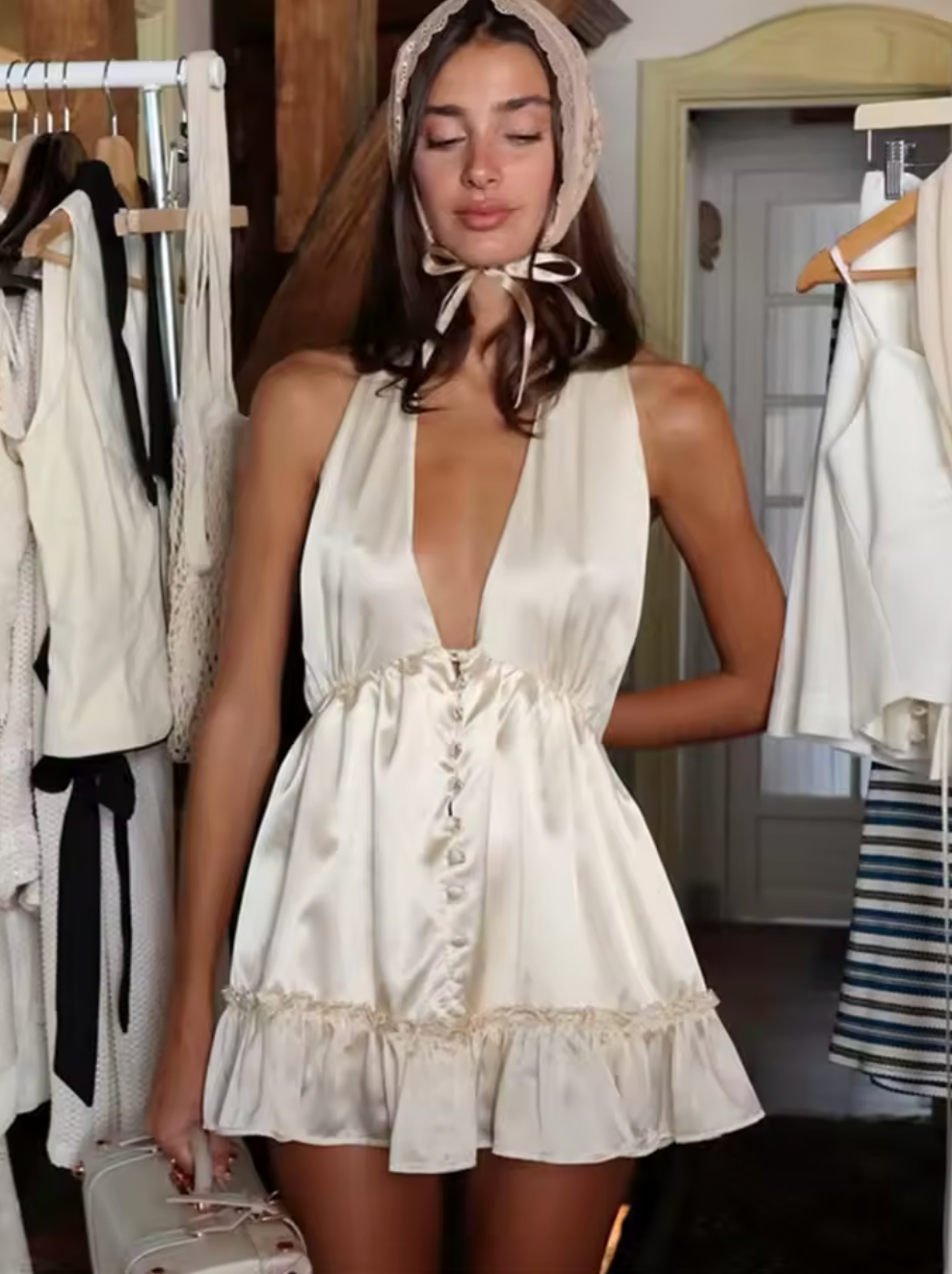 The Caroline Dress by Fait par Foutch is crafted from medium-weight 100% silk charmeuse, offering a luxurious, smooth texture that drapes elegantly. Fully lined with pure silk for enhanced comfort, it features functional silk-covered buttons and loops down the center front. Its low V-neckline and halter straps tie into an adjustable bow at the neck, providing a customizable fit. The low back design includes hidden elastic at the waist, ensuring a flattering silhouette and secure fit. 