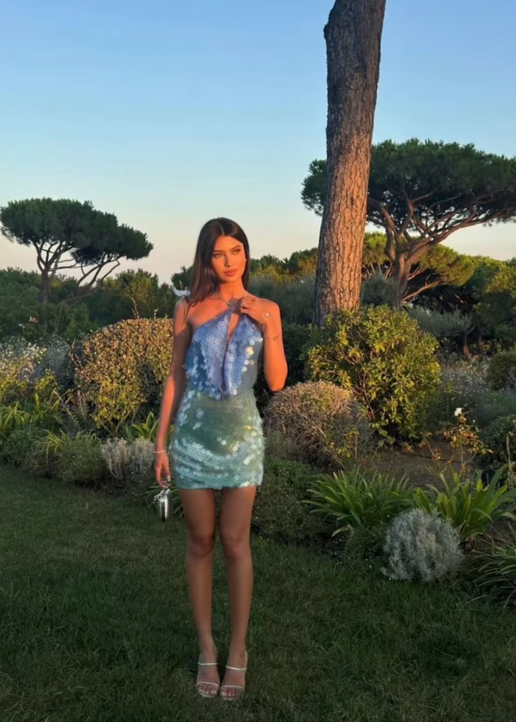 The Kiki Mini Dress dazzles with a molten sequin design that shifts in an ombré gradient from blue to green, capturing light with every movement. Its slinky silhouette is ideal for summer evenings, enhanced by a daring plunge back and an extreme cowl neckline that together create a strikingly sensual appeal. Perfect for making a bold statement at any night event.