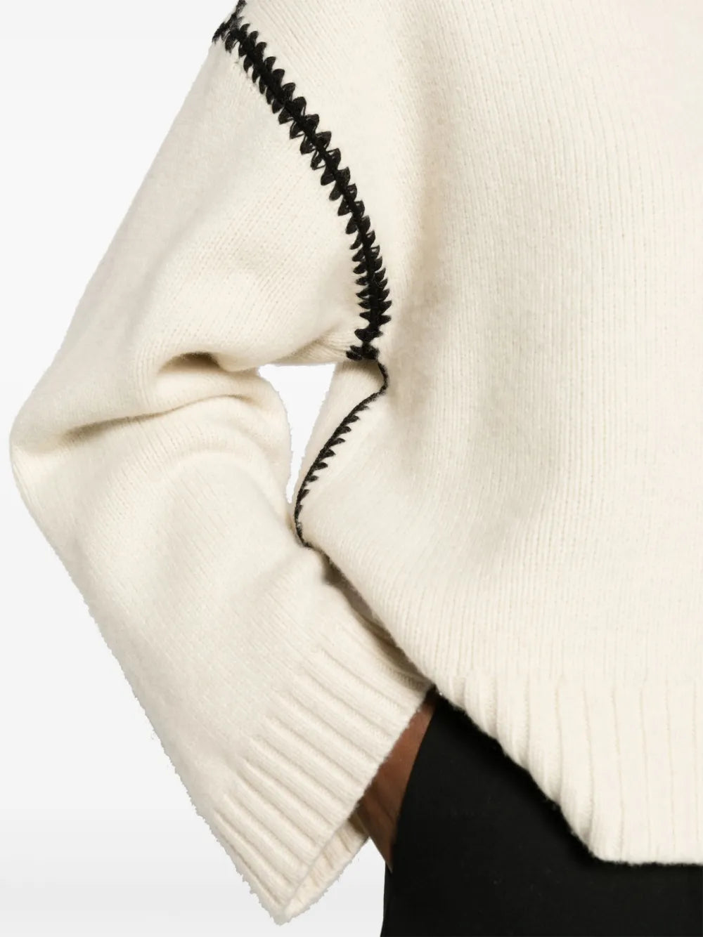 This TOTEME wool jumper exemplifies contemporary minimalism with refined craftsmanship. Constructed from pure wool in a pristine cream-white, it features distinctive black whipstitch detailing that adds subtle visual interest without compromising the brand's signature understated aesthetic. The relaxed silhouette includes drop shoulders and generously proportioned long sleeves, while ribbed cuffs and hem provide structure and definition. 