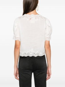 Introducing the luxurious Idella top by DOEN. Made from high-quality, soft ramie and delicate guipure lace, this top boasts a flattering V-neck and elegant scallop hem. Its front button fastening and short puff sleeves add a touch of sophistication to this white beauty. Upgrade your wardrobe with the Idella top.