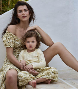 Crafted from soft, lightweight organic cotton voile, the Ashlynn Dress in Citron Rosier Floral by Doen blends Victorian elegance with modern comfort. Featuring short puffed sleeves, a scoop neckline with a functional center tie, and delicate ruffled cuffs, this dress exudes vintage charm. The smocked bodice ensures a flattering fit, complemented by an adjustable waist tie, while the full, ankle-grazing skirt offers graceful movement. Ideal for those seeking refined style with breathable, sustainable fabric.