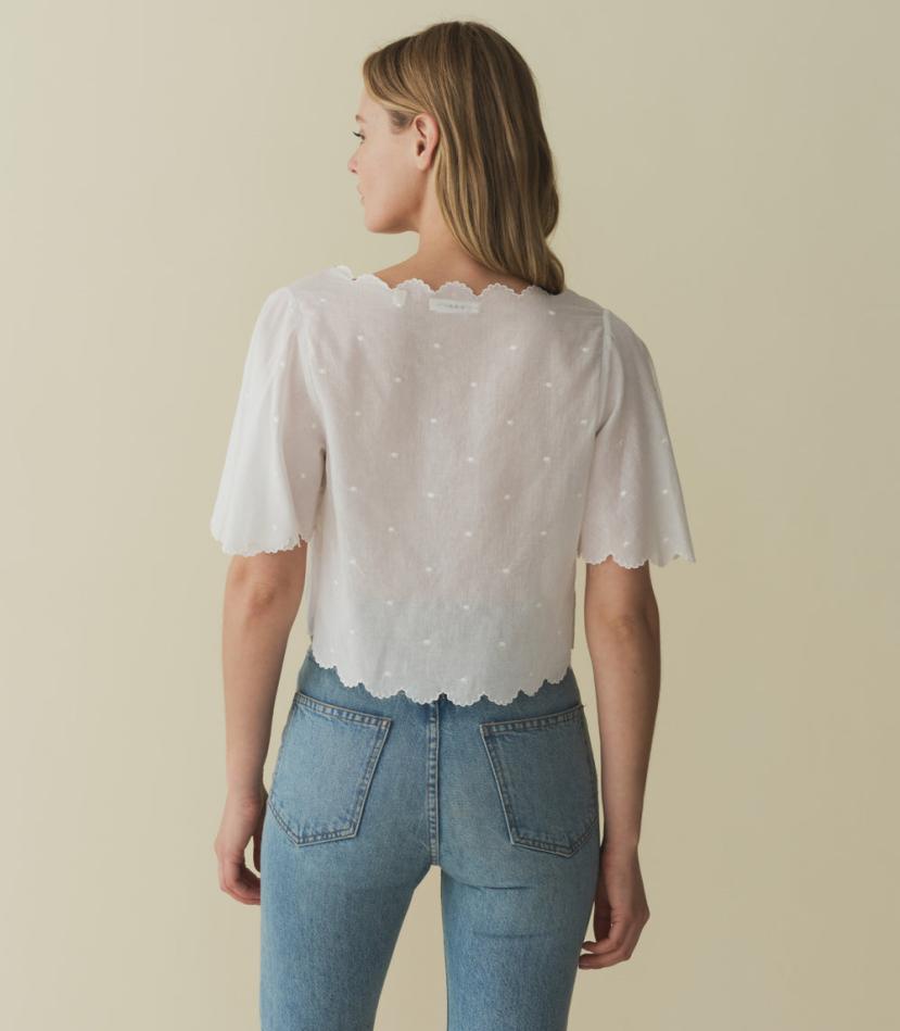 Indulge in the romantic charm of the Kacy Embroidered Top by DOEN, crafted with 100% organic cotton voile and adorned with delicate bow embroidery and playful cutouts. Inspired by vintage Victorian blouses, this top features elegant scalloped details and breezy sleeves that add a touch of sophistication. Elevate your wardrobe with this luxurious and exclusive piece.