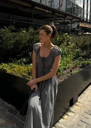 Experience effortless elegance in the Quinn Maxi Dress. The scoop neckline is accented with an adjustable tie, while the puffed sleeves and gathered bust add a touch of femininity. The fitted bodice with elasticized smocking creates a flattering silhouette, flowing into an ankle-grazing A-line skirt. Embrace sophistication with ease.