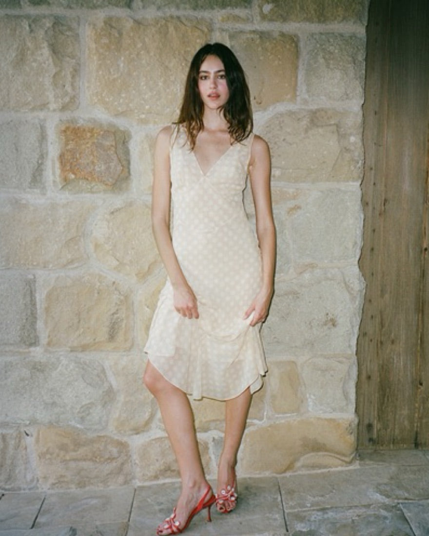 The Cleo Dress in Honey Spot by Realisation embodies effortless femininity with its light, floaty fabric and delicate sheer design. Featuring a flattering plunging V-neckline, sculpting panelled waist, and a fluted skirt that drapes gracefully, this dress is perfect for warm summer days and sultry evenings. The slightly shorter hemline adds a playful touch, while the removable underslip allows you to customize your look—opt for bold sheerness or a more refined silhouette. 