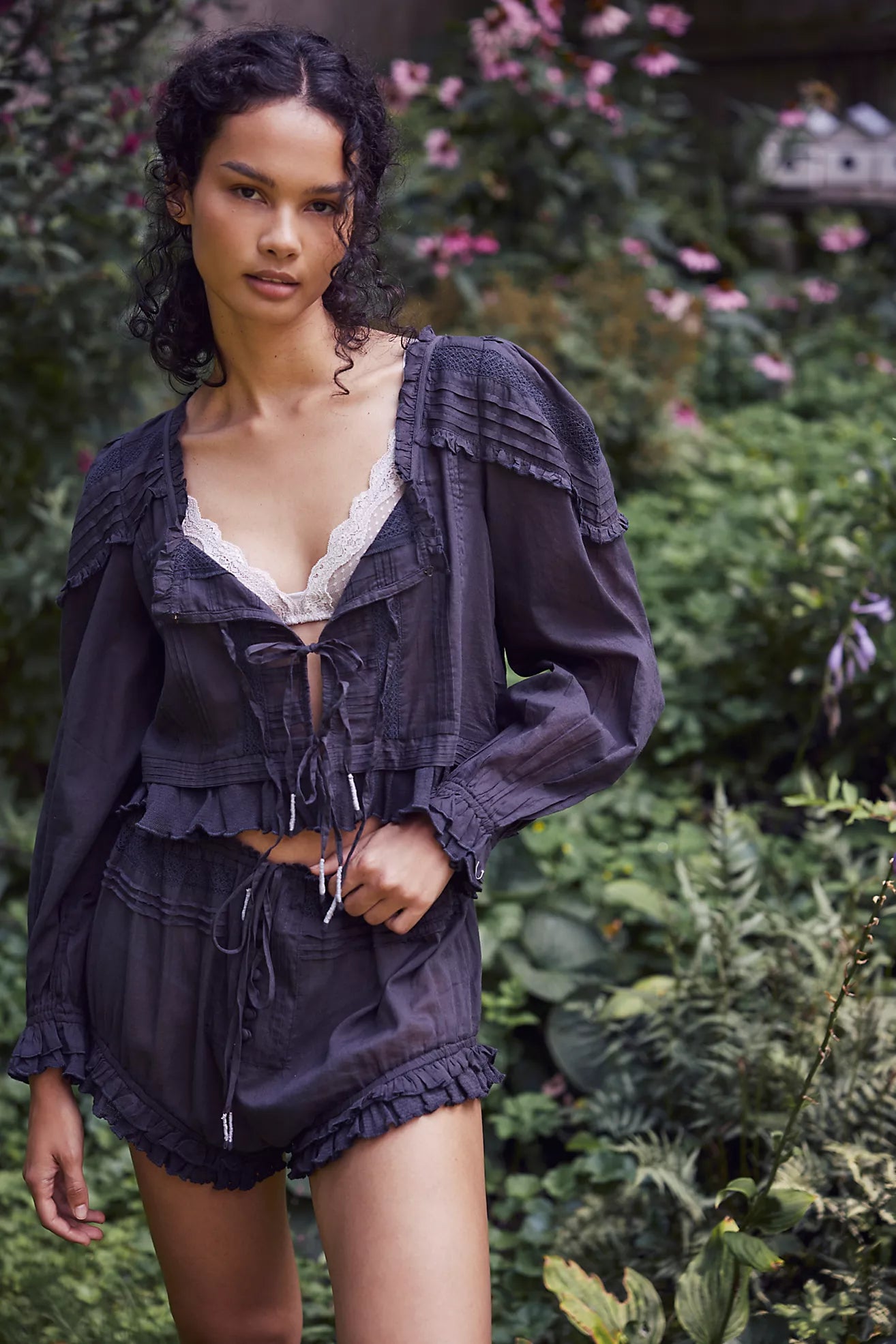 Experience timeless elegance with the Florence Set in Black, designed for both comfort and style. The structured bed jacket features front tie closures, delicate pleated piecing, and banded trumpet sleeves accented by intricate embroidery and ruffle trim. Coordinating shorts offer a drawstring waist for a customizable fit, complemented by ruffle details, pleated patterns, and embroidered accents with a graceful curved hem. Perfect for lounging with refined sophistication.