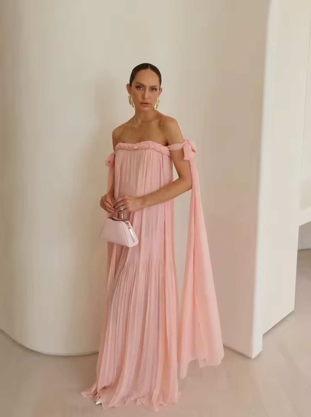 Elevate your elegance with this draped floor-length dress featuring an intricate braided neckline and a corset bodice lining for subtle structure. The tie arm straps flow gracefully into a train, complementing the relaxed silhouette. An invisible back zip closure ensures a seamless finish, while the sheer tulle lining adds delicate dimension to this sophisticated design.