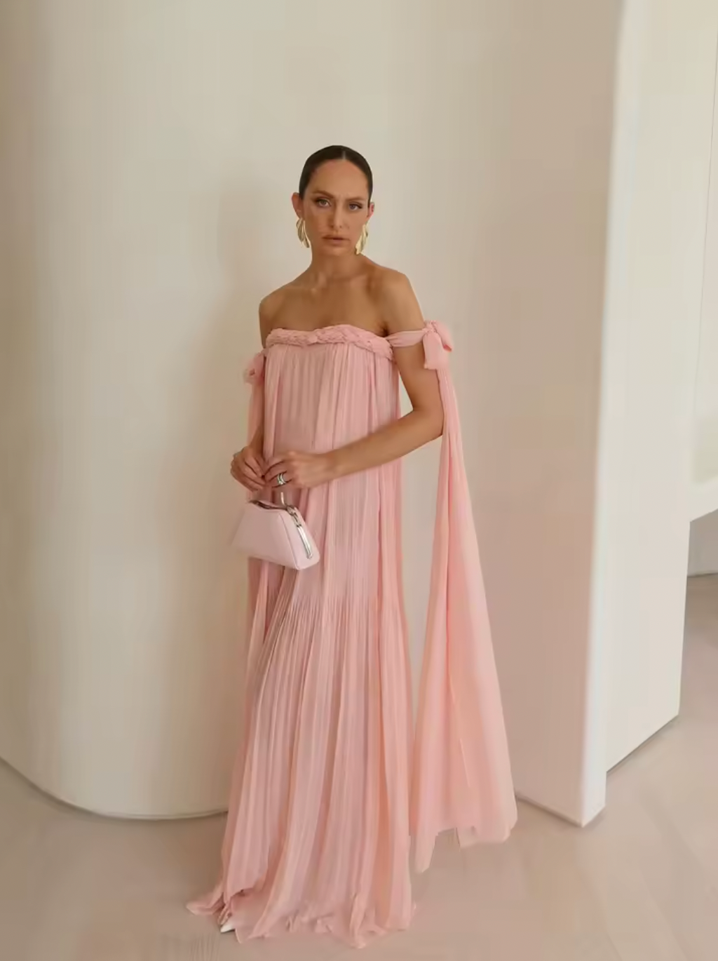 Elevate your elegance with this draped floor-length dress featuring an intricate braided neckline and a corset bodice lining for subtle structure. The tie arm straps flow gracefully into a train, complementing the relaxed silhouette. An invisible back zip closure ensures a seamless finish, while the sheer tulle lining adds delicate dimension to this sophisticated design.