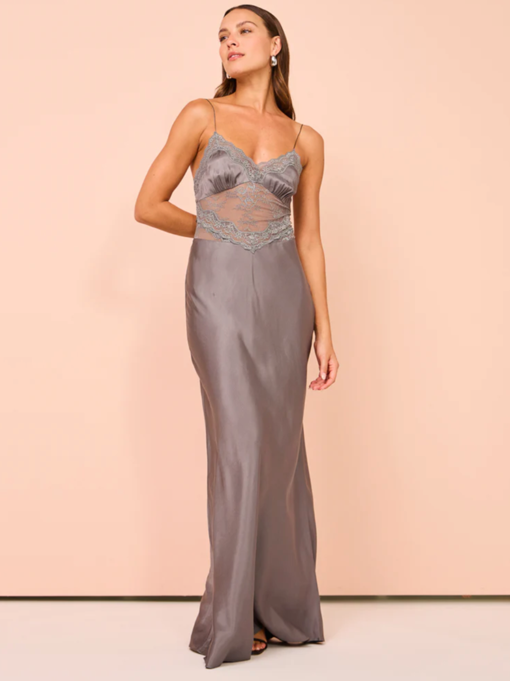 The Amoras Gown in Grey combines elegance and sophistication with its satin-feel fabric and expertly crafted details. Highlighted by a flattering V neckline and stretch lace midsection, it offers both comfort and subtle allure. The gathered bust cups enhance the silhouette, while a delicate lace trim along the neckline adds a refined, feminine touch. Ideal for formal occasions, this gown balances timeless style with modern design for a graceful statement.