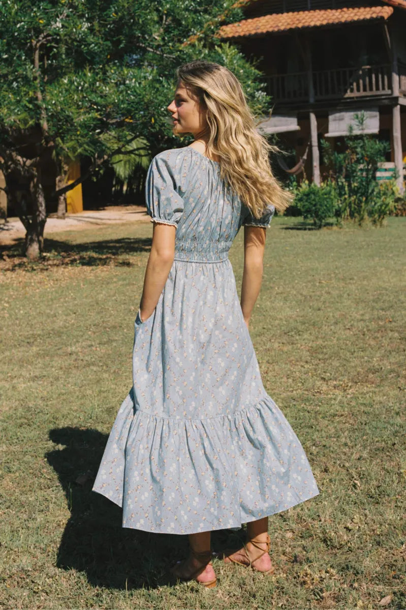 The Brynne Dress in the seasonal Pansy Blues print by Christy Dawn combines delicate femininity with adjustable comfort. It features a low scoop neckline complemented by a drawstring tie at both the neck and waist, allowing a custom fit that enhances your silhouette. Elasticated seams ensure ease of movement, making this dress as practical as it is stylish for versatile wear throughout the season.