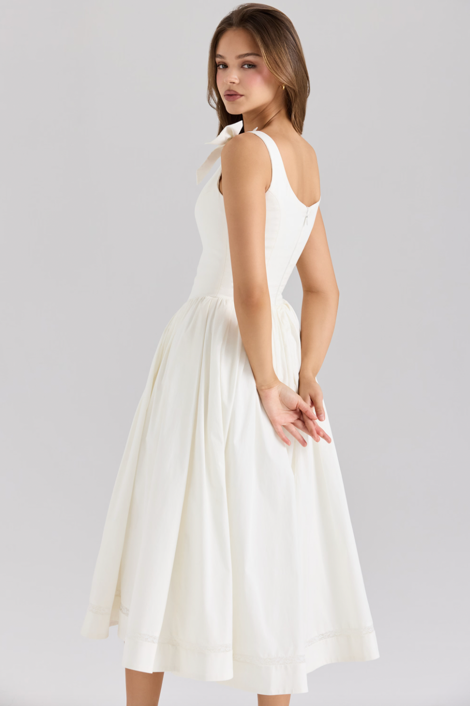 The Lillia Midi Dress exemplifies refined elegance with its expertly crafted stretch cotton fabric that contours the body comfortably. Its structured bodice features fabric-covered buttons along the front, designed to flatter your silhouette. Flowing from the hips, the skirt offers a delicate volume enhanced by a soft tulle lining and a lace-trimmed hem, creating a graceful and sophisticated look with every movement.