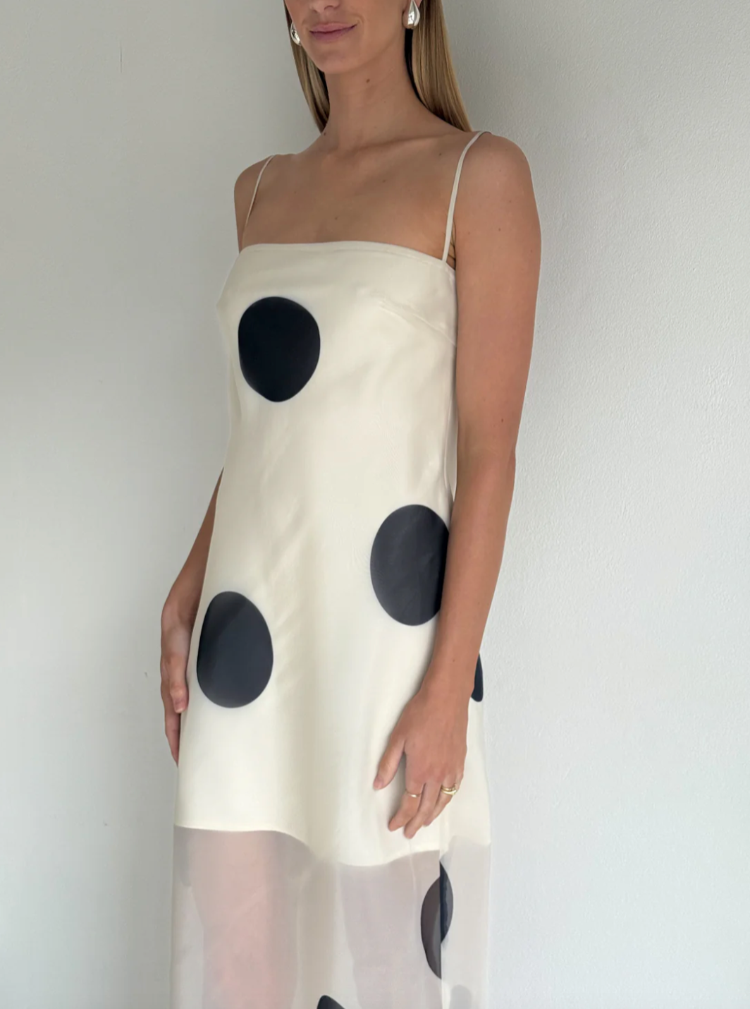 The Mila Maxi Dress in Ivory Polka by Nicole features sheer organza adorned with striking polka dots, shaping a sleek column silhouette. Its half-lined design and elasticated back ensure comfort and adaptability, while the option to wear it with or without straps provides versatile styling choices perfect for refined occasions.