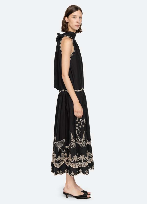 The Kingsley embroidered tank dress by SEA NY showcases intricate embroidery throughout its design, offering a refined and elegant appeal. It features a high neckline that adds a sophisticated touch, complemented by a delicate back bow tie for adjustable fit and added charm. The scalloped hemline enhances the dress's feminine silhouette, making it an exceptional choice for those seeking a polished yet distinctive look.