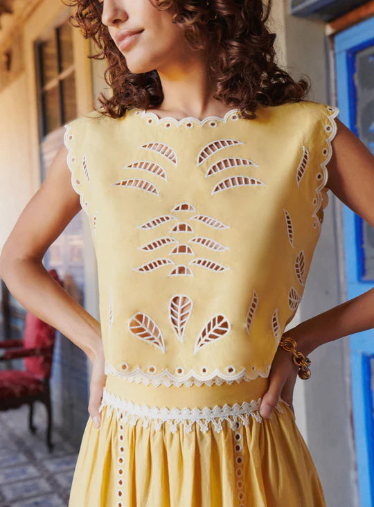 The Tiffany Set combines a vibrant skirt and top, expertly crafted to elevate your seasonal wardrobe. The skirt features intricate openwork patterns and a scalloped hem, enhanced with modernized iconic embroidery using inlaid guipure, adding refined elegance. The top complements with its sunny tone and delicate embroidery, versatile enough for pairing with high-waisted jeans or the matching skirt for a coordinated, feminine ensemble. 