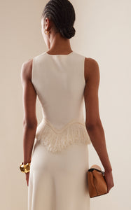 The 'Paulina' skirt offers a graceful A-line shape that gently widens toward its distinctive zig-zag fringe-trimmed hem. Complete the look by pairing it with the coordinating 'Koa' top, which boasts a sleek, sleeveless design accented by a matching zig-zag fringe detail at the hem.