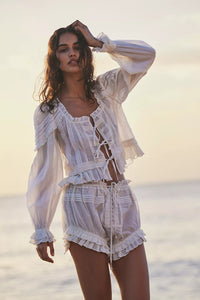 Embrace timeless elegance with the Florence Bed Jacket Set, designed for sophisticated comfort. The structured bed jacket features front tie closures, pleated details, banded trumpet sleeves, and delicate embroidery, offering a refined vintage appeal. Coordinating button-front shorts include a drawstring waist, ruffle trimming, pleated accents, and an embroidered curved hem, ensuring an effortless, flattering fit. This set blends classic style with ease, perfect for lounging with grace and poise.