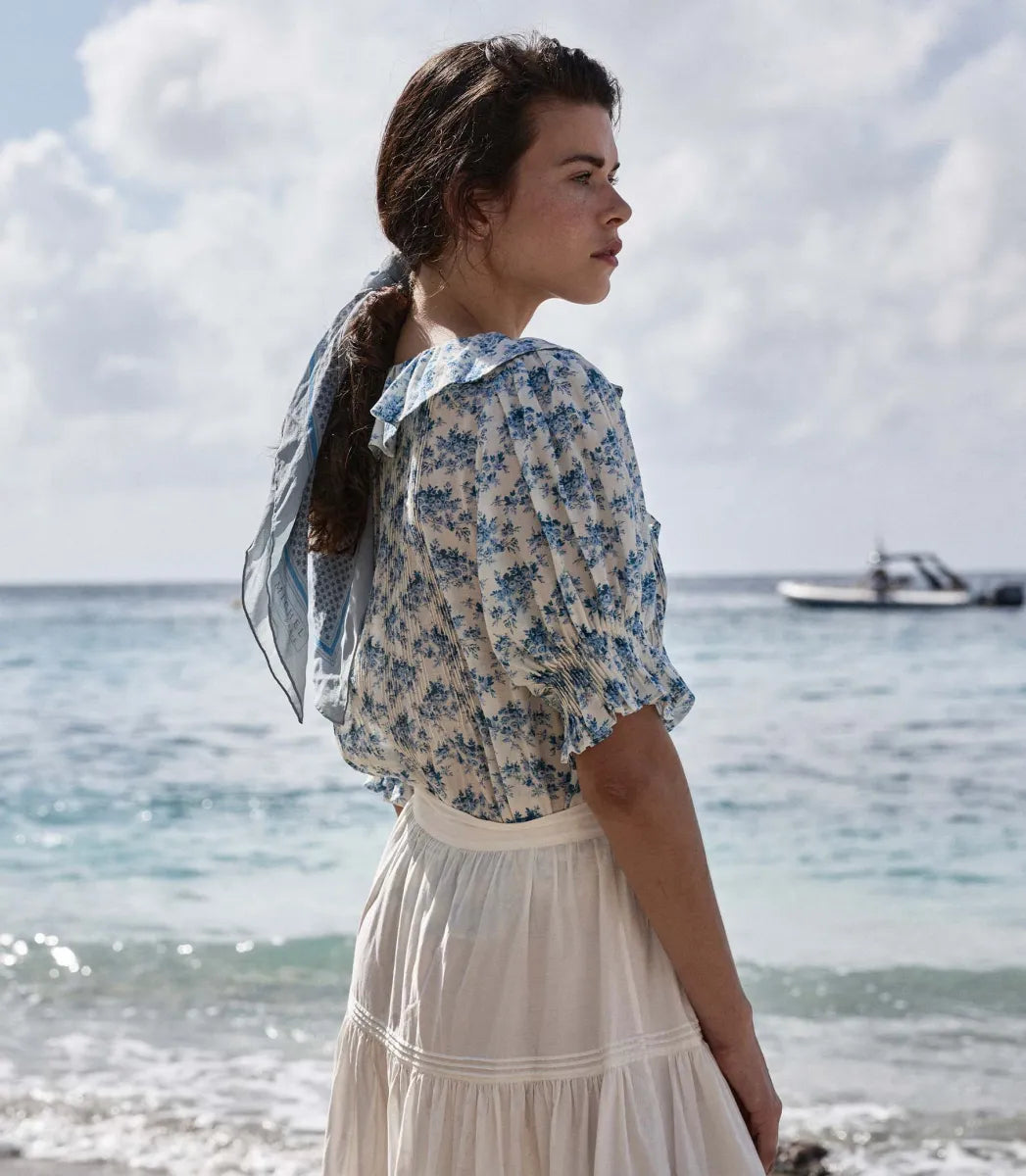 The Henri top in Bleu Rosier Floral offers a refined yet approachable style, crafted from soft fabric adorned with a delicate blue floral pattern. Its subtle ruffle detail and V-neckline enhance the rustic charm while the gently fitted silhouette flatters the figure. Pair it effortlessly with blue denim for versatile looks that transition seamlessly from casual daywear to polished evening ensembles with the right footwear choice.