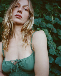 The Camille in Poison by Realisation Par blends chic minimalism with versatile design. Crafted from solid-colored silk, it features a milk-maid style bust with a keyhole detail that can be tied for added lift or left untied for a relaxed, elegant look. The form-fitting elasticated torso and back, adjustable straps, and bias-cut skirt ensure a flattering fit on various body shapes. Pair with kitten heels to complete a sophisticated yet effortlessly alluring ensemble.