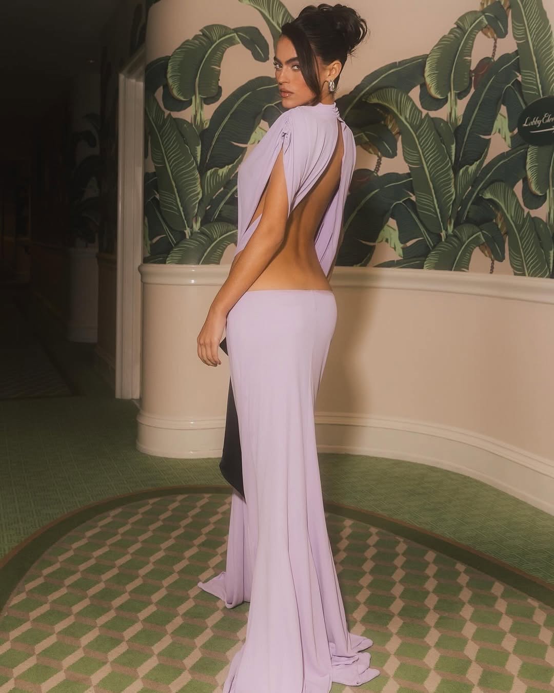 The Constantina Jersey Dress with Bow by Helsa features a sophisticated pull-on design for effortless wear. Crafted from soft jersey fabric, it offers partial lining for comfortable coverage while maintaining breathability. Distinctive cut-out details at the back and waist add a modern, elegant touch, complemented by a delicate satin bow for refined contrast. This dress combines comfort with stylish accents, making it an excellent choice for both casual and dressy occasions.