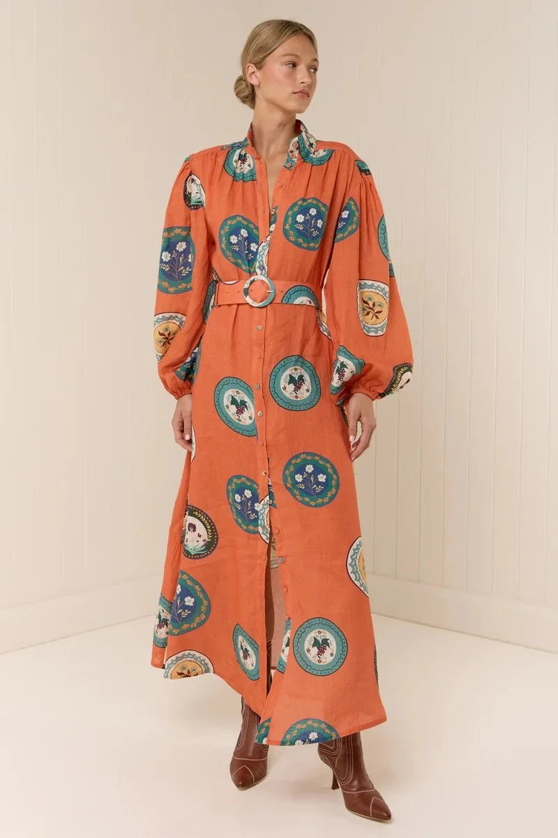 The Noddy Dress in Orange Plates by Palm Noosa showcases a refined midi silhouette crafted from 100% premium linen. Its relaxed fit is complemented by elegant blouson sleeves with elasticated cuffs, a sleek stand collar, and a button-front design. A matching buckle belt allows you to define your waist gracefully, enhancing the dress’s flattering drape. Perfect for an effortless yet polished look, this dress combines comfort and style with sophisticated ease. Please consult our size guide for the best fit.