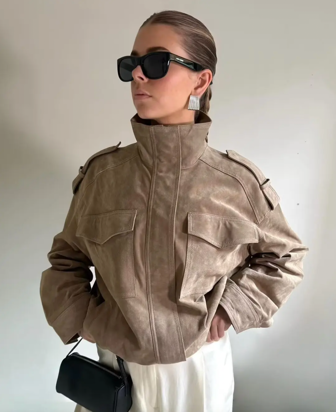 This Suede Jacket combines timeless sophistication with practical design. Crafted from soft suede leather, it features a high collar that provides extra warmth and a refined look. Long cuffed sleeves with shoulder tabs enhance its rugged appeal, while front and chest flap pockets offer convenient storage without sacrificing style. 