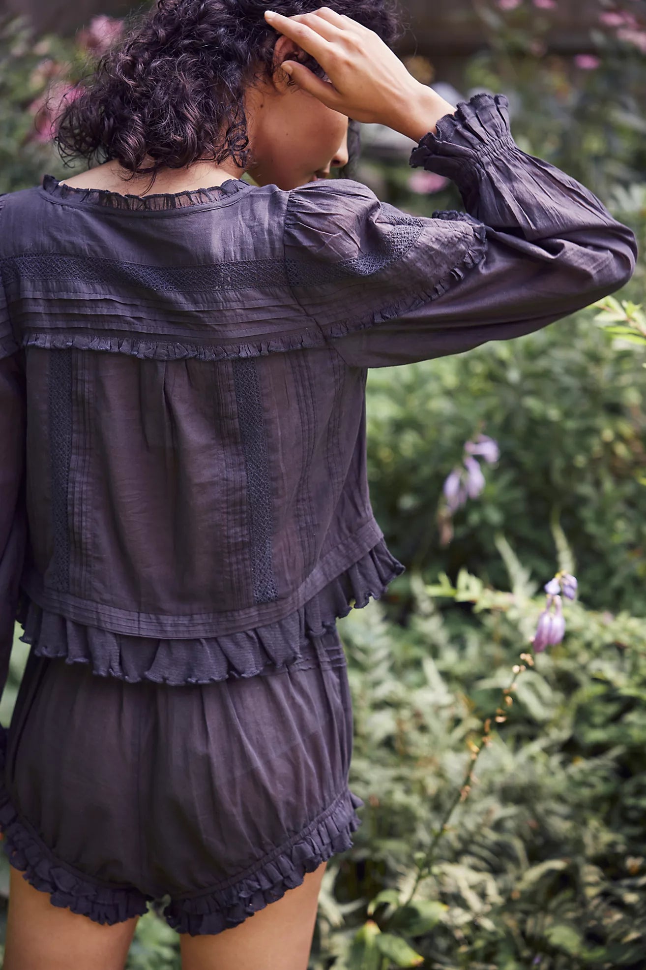 Experience timeless elegance with the Florence Set in Black, designed for both comfort and style. The structured bed jacket features front tie closures, delicate pleated piecing, and banded trumpet sleeves accented by intricate embroidery and ruffle trim. Coordinating shorts offer a drawstring waist for a customizable fit, complemented by ruffle details, pleated patterns, and embroidered accents with a graceful curved hem. Perfect for lounging with refined sophistication.