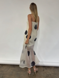 The Mila Maxi Dress in Ivory Polka by Nicole features sheer organza adorned with striking polka dots, shaping a sleek column silhouette. Its half-lined design and elasticated back ensure comfort and adaptability, while the option to wear it with or without straps provides versatile styling choices perfect for refined occasions.