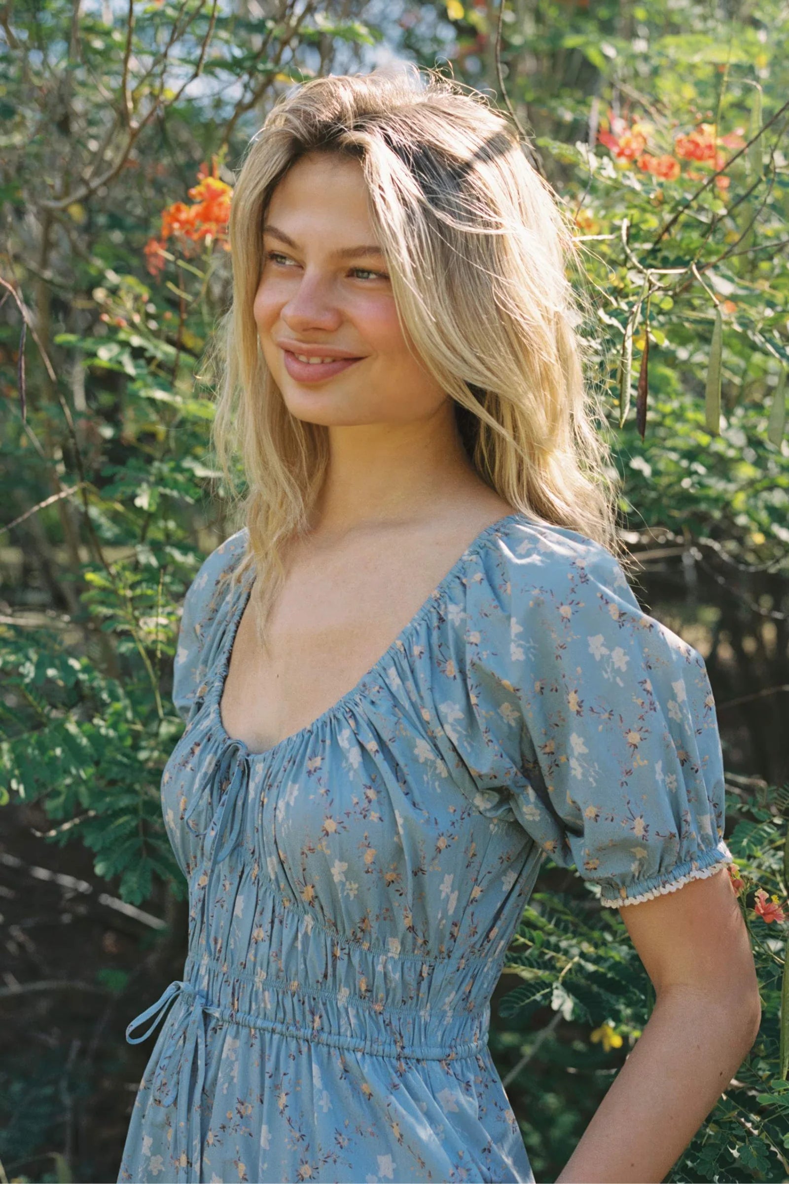 The Brynne Dress in the seasonal Pansy Blues print by Christy Dawn combines delicate femininity with adjustable comfort. It features a low scoop neckline complemented by a drawstring tie at both the neck and waist, allowing a custom fit that enhances your silhouette. Elasticated seams ensure ease of movement, making this dress as practical as it is stylish for versatile wear throughout the season.