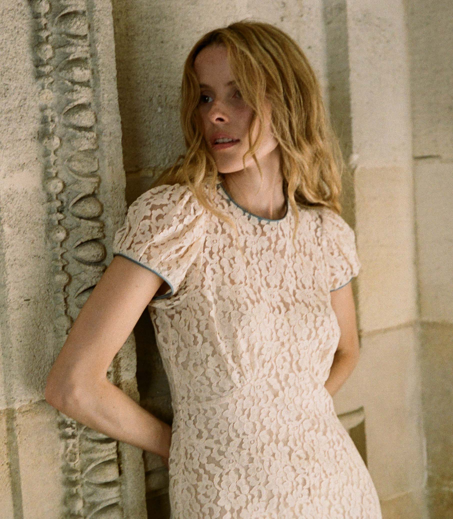 The Katarina Dress by Doen features a refined silhouette crafted from delicate corded lace, enhanced with satin trims along the neckline and puffed sleeves. Designed with a full lining, it offers both elegance and assured coverage, making it a sophisticated choice for special occasions.