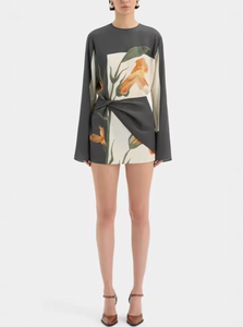 The Constance Twist Mini Dress is made from delicate silk crepe adorned with artistic floral prints and bold borders. This dress offers a relaxed silhouette, showcasing long sleeves with gentle flares and a distinctive contrasting overlay accented by a twisted detail at the waist.