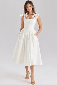 The Lillia Midi Dress exemplifies refined elegance with its expertly crafted stretch cotton fabric that contours the body comfortably. Its structured bodice features fabric-covered buttons along the front, designed to flatter your silhouette. Flowing from the hips, the skirt offers a delicate volume enhanced by a soft tulle lining and a lace-trimmed hem, creating a graceful and sophisticated look with every movement.