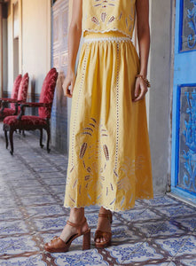 The Tiffany Set combines a vibrant skirt and top, expertly crafted to elevate your seasonal wardrobe. The skirt features intricate openwork patterns and a scalloped hem, enhanced with modernized iconic embroidery using inlaid guipure, adding refined elegance. The top complements with its sunny tone and delicate embroidery, versatile enough for pairing with high-waisted jeans or the matching skirt for a coordinated, feminine ensemble. 