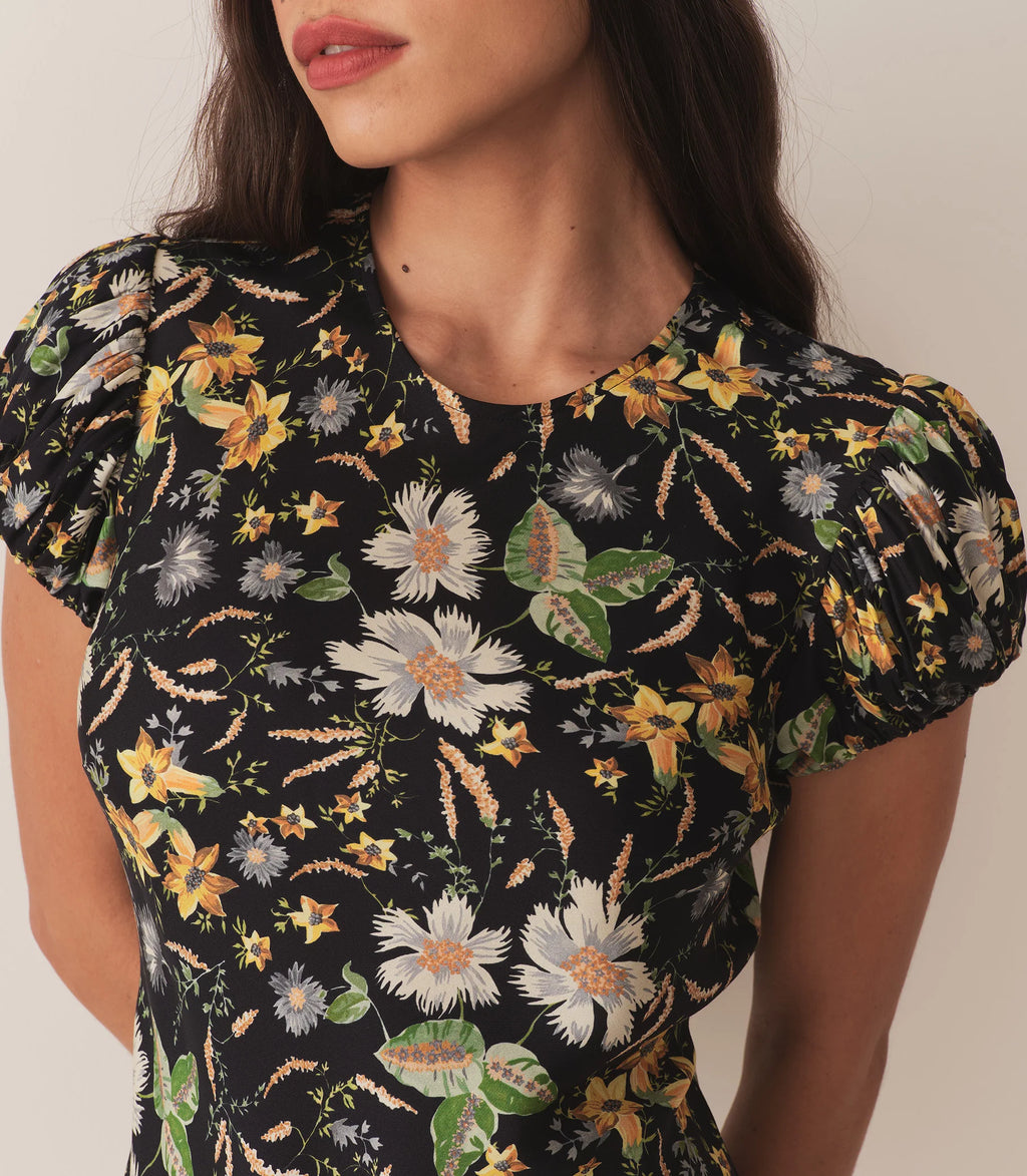 Crafted from a drapey silk-viscose twill, the Merla Dress by Doen in Sweet Anemone boasts an elegant bias cut that flatters the silhouette. Inspired by Art Deco motifs, this dress features a refined high neck and delicate short puffed sleeves, blending timeless style with modern sophistication. Perfect for occasions that call for understated glamour.