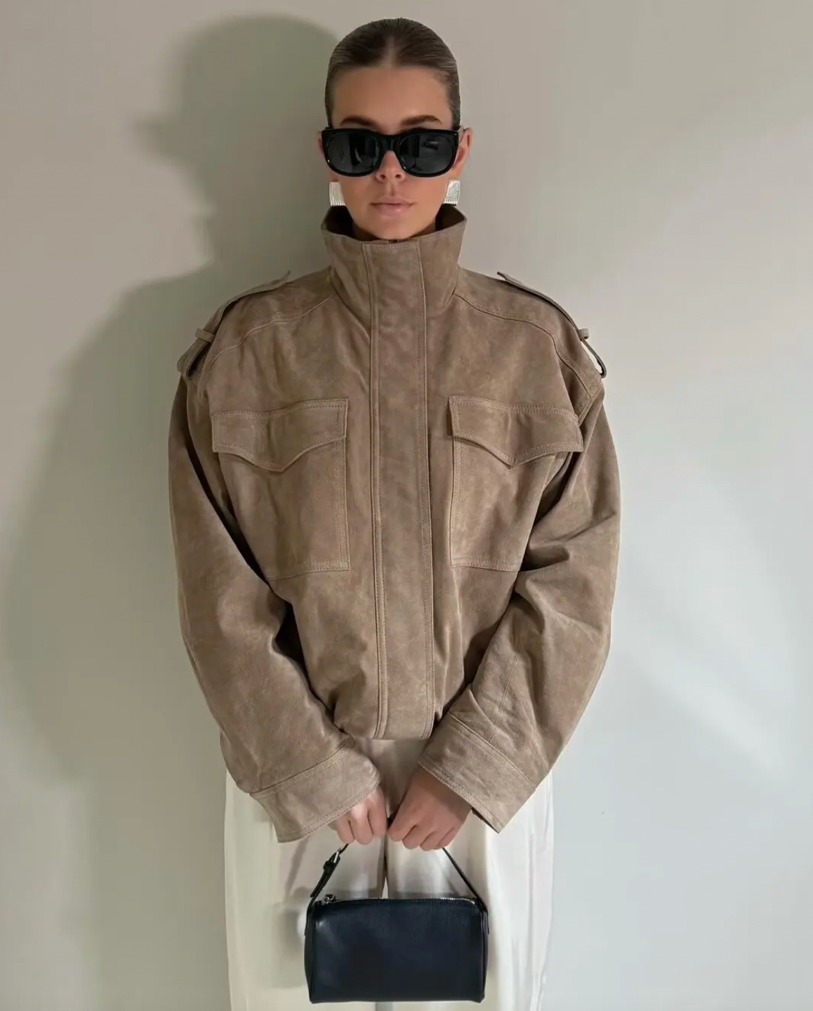 This Suede Jacket combines timeless sophistication with practical design. Crafted from soft suede leather, it features a high collar that provides extra warmth and a refined look. Long cuffed sleeves with shoulder tabs enhance its rugged appeal, while front and chest flap pockets offer convenient storage without sacrificing style. 