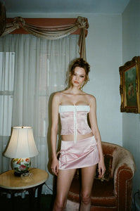 Discover effortless style with the Serena Mini Skirt by With Jean. This low rise, mini length skirt is designed to sit comfortably on your hips, while the back zip closure provides a seamless finish. The cinched bow detailing at the front adds a touch of sophistication to your ensemble. Elevate your look with this luxurious piece.