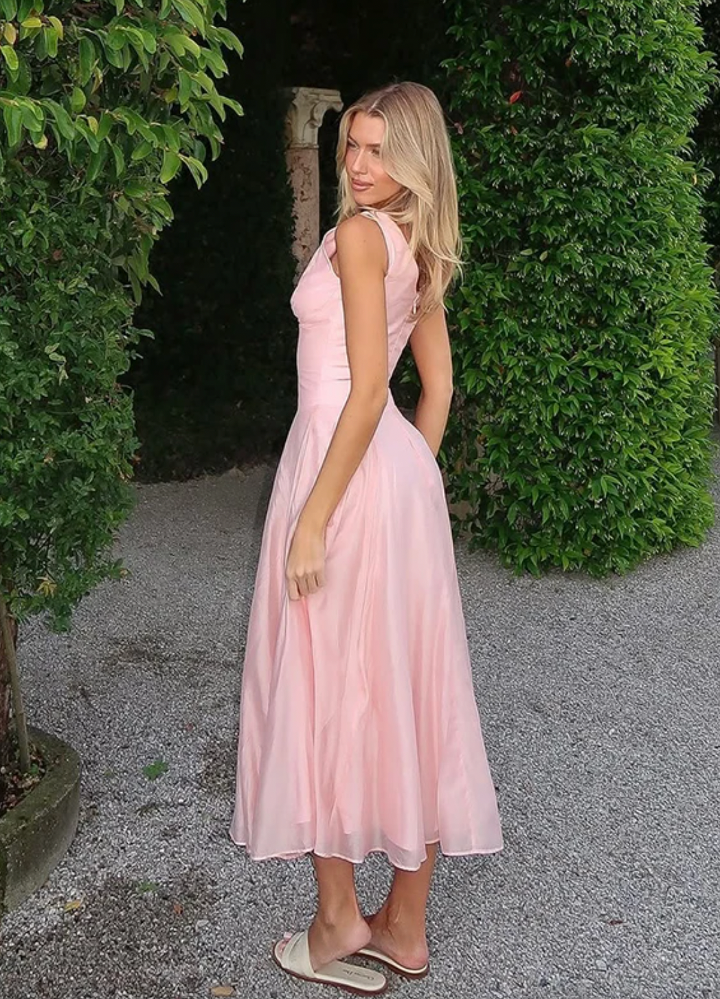 Crafted from lightweight pink chiffon, the 'Samira' midi dress combines elegance with effortless movement. Its classic V-neckline and signature boning offer a tailored silhouette that flatters the bust and defines the waist. Front buttons enhance the refined fit, while subtle pleats in the skirt create graceful flow, adapting naturally to your movements. Designed to leave a lasting impression, this dress exemplifies sophisticated style with expert attention to detail.