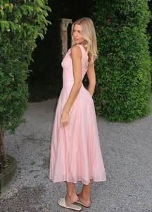 Crafted from lightweight pink chiffon, the 'Samira' midi dress combines elegance with effortless movement. Its classic V-neckline and signature boning offer a tailored silhouette that flatters the bust and defines the waist. Front buttons enhance the refined fit, while subtle pleats in the skirt create graceful flow, adapting naturally to your movements. Designed to leave a lasting impression, this dress exemplifies sophisticated style with expert attention to detail.