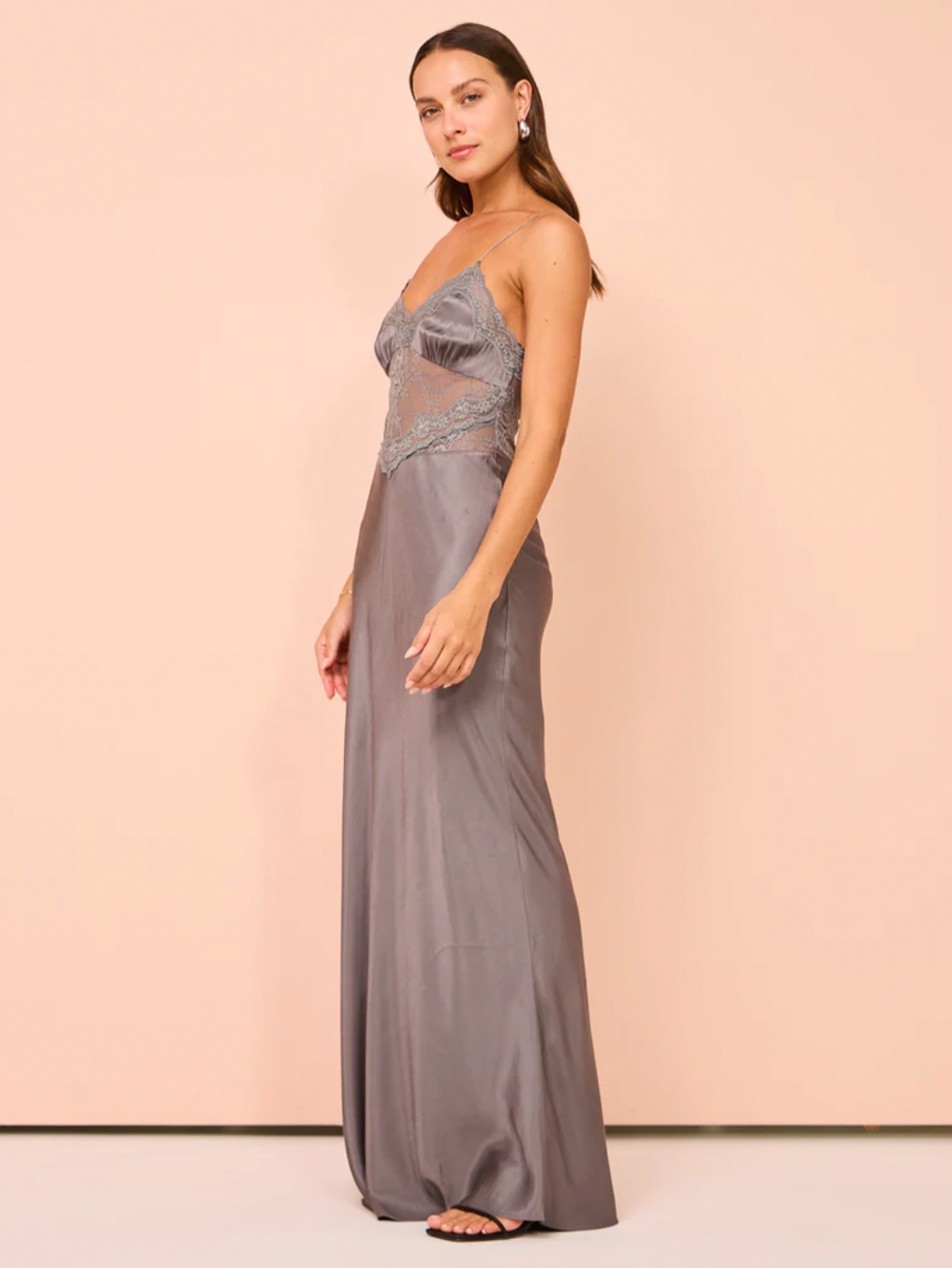The Amoras Gown in Grey combines elegance and sophistication with its satin-feel fabric and expertly crafted details. Highlighted by a flattering V neckline and stretch lace midsection, it offers both comfort and subtle allure. The gathered bust cups enhance the silhouette, while a delicate lace trim along the neckline adds a refined, feminine touch. Ideal for formal occasions, this gown balances timeless style with modern design for a graceful statement.